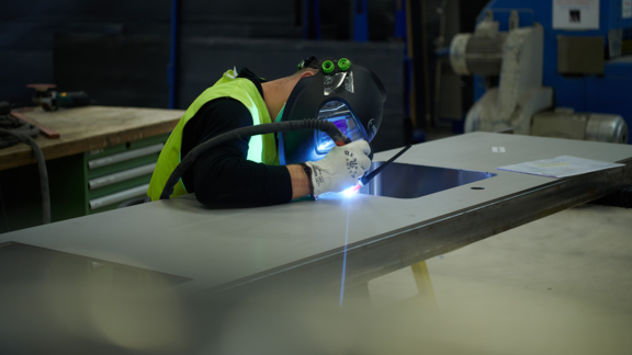 BORA-Mitarbeiter schweißt präzise ein Bauteil für BORA-Küchengeräte in der Produktionswerkstatt.