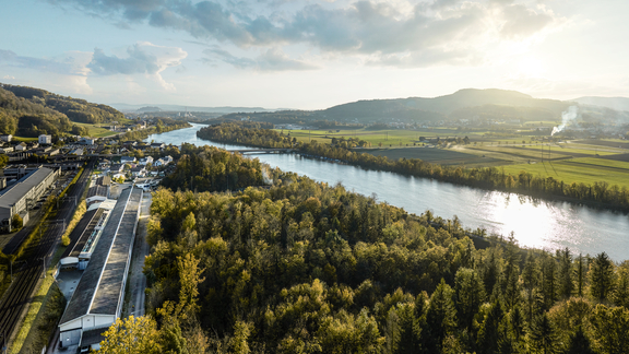 Luftaufnahme des BORA Werks im Grünen an einem Fluss, umgeben von Wald und hügeliger Landschaft.