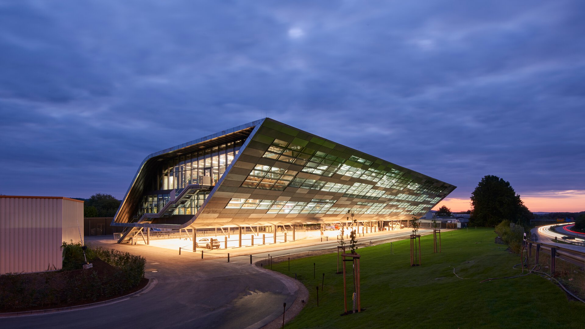 BORA Hauptgebäude bei Abenddämmerung mit beleuchteter Glasfassade und modernem, futuristischem Design.