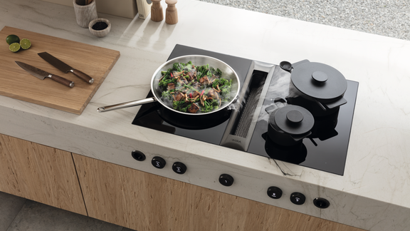 BORA Kochfeld mit integriertem Dunstabzug, Töpfen und Schneidebrett mit Küchenmessern in moderner Küche.